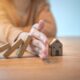 A hand stops the risk of wooden block of a miniture home