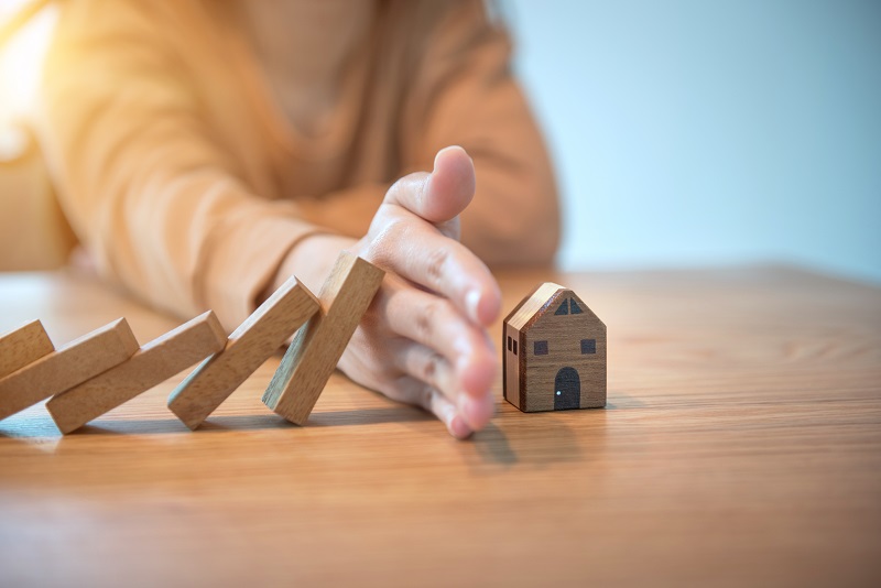 A hand stops the risk of wooden block of a miniture home